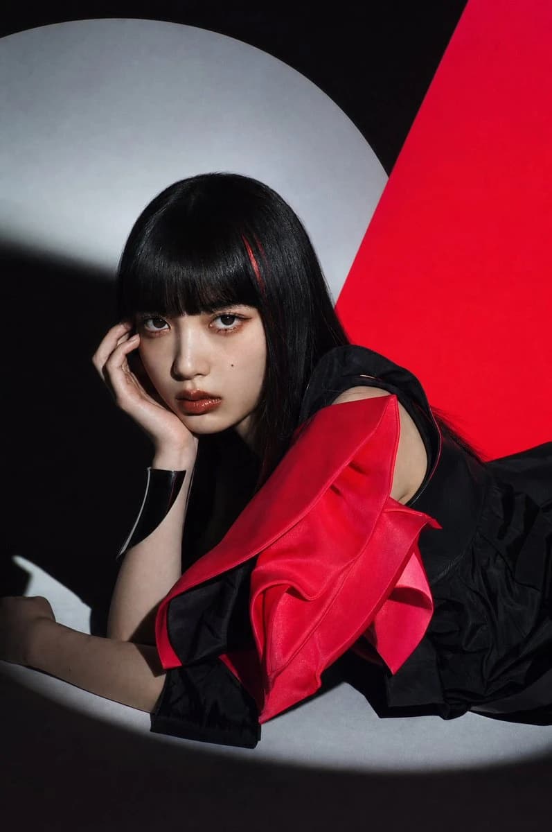Avant-garde fashion portrait of a woman in black and crimson fabric against bold red and gray shapes
