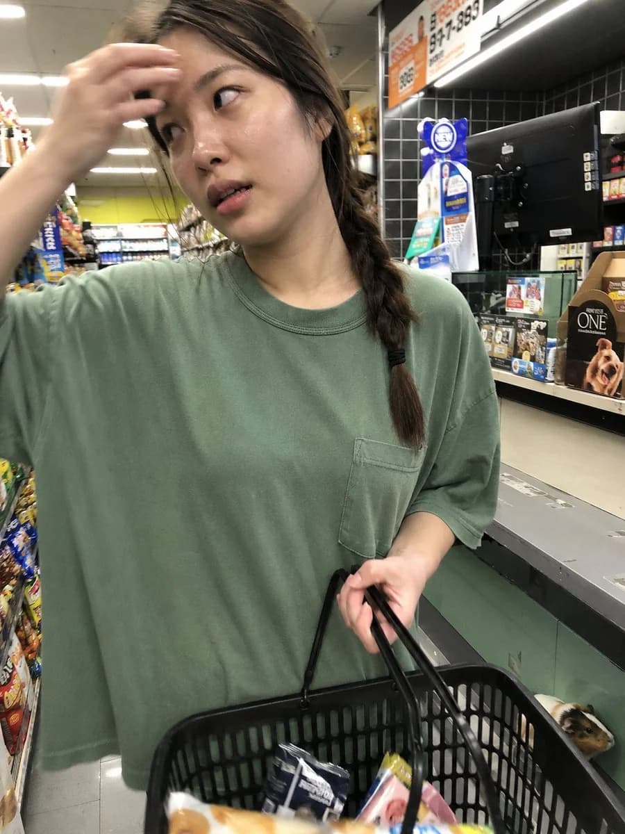 A candid iPhone-style convenience store portrait of a young Korean woman at checkout under bright fluorescent lighting
