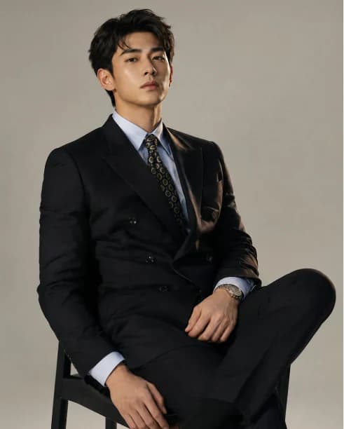 A high-end Chinese fashion magazine portrait of a confident male model with sharp styling, gray gradient backdrop, and editorial polish