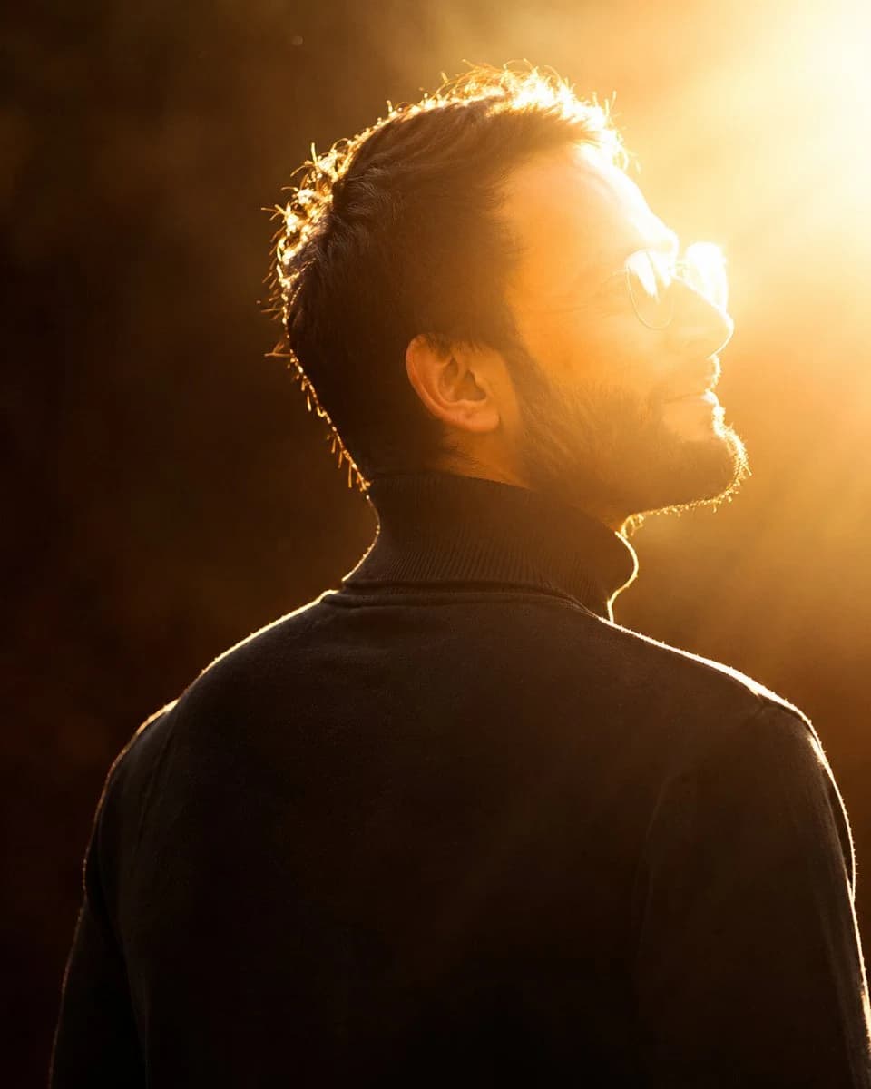 Cinematic backlit portrait of a person in warm golden-hour light, with sharp facial detail and dramatic rim lighting.