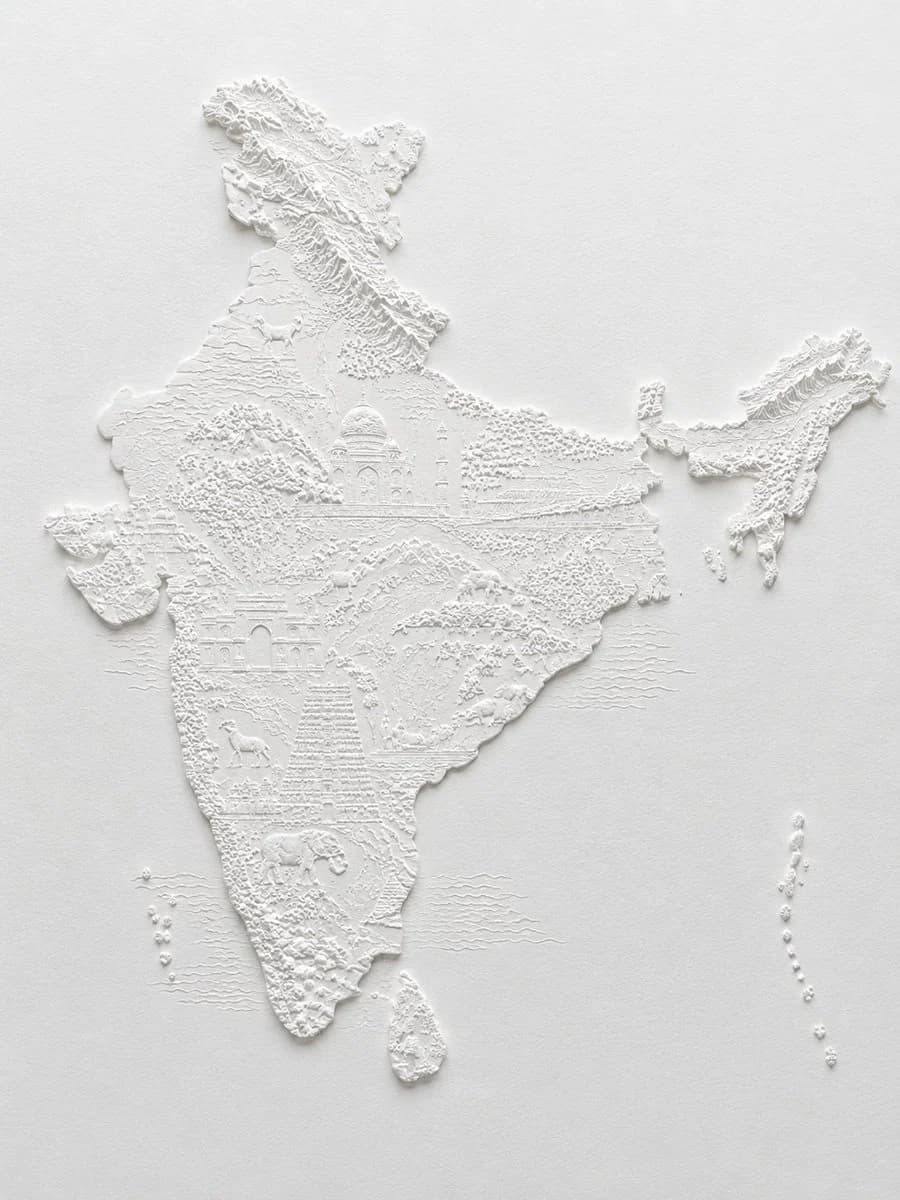 A monochrome white bas-relief paper sculpture map of India with raised landforms, warm paper texture, and crisp shadows